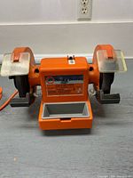 Front view of Black & Decker orange 6 in bench grinder showing both wheels, eye shields, tool rests and parts tray