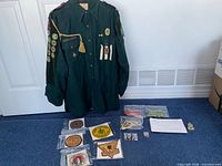 Full view of uniform shirt hanging with accessories laid out below
