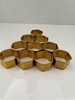 All ten brass hexagonal napkin rings stacked in triangular formation