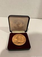 Medallion in open case showing globe logo side