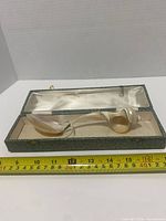 Spoon laid in open case with tape for scale