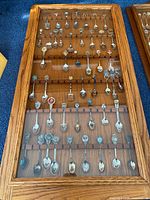 Front view of closed wooden display case filled with souvenir spoons