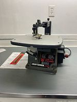 Full view of Craftsman scroll saw on table showing cast-iron work surface and base branding