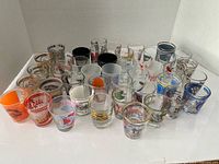Group view of approximately 28 souvenir shot glasses