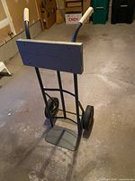 Front angled view of hand truck showing frame, wheels, toe plate, wood pad
