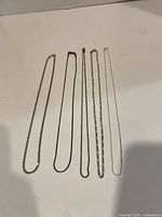 Five sterling silver necklaces laid side-by-side to show chain styles