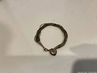 Bracelet laid flat showing multiple strands, end caps, clasp, heart charm
