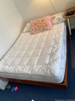 Full view of queen bed with mattress on teak platform frame