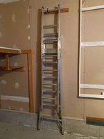 Full front view of aluminum combination ladder leaning against wall