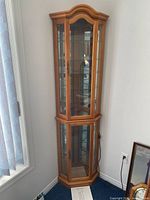 Full view of oak corner curio cabinet in room