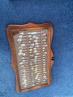 Closed view of wooden display case holding souvenir spoons