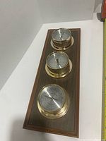 Full view of three-instrument weather station on wood plaque