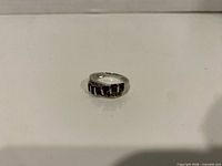 Front view of sterling silver band ring with red stones