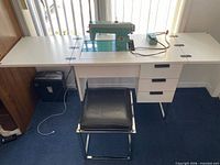 Full view of cabinet, sewing machine installed, stool in front