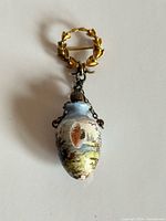 Front view showing gold wreath pin and hanging enamel bottle