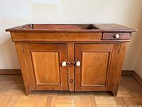 Front view of pine dry sink showing double doors, porcelain knobs, legs, and overall form