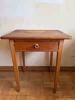 Front view of pine side table showing drawer and tapered legs