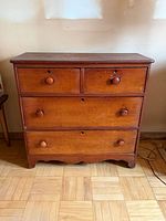 Front view showing four drawers, knob pulls, bracket base