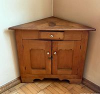 Full view of corner cabinet front, showing drawer, doors and overall shape