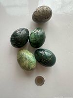 All five marble eggs next to coin for scale