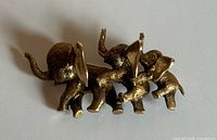Front view of three-elephant gold brooch