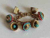 Full view of bracelet showing six textured gold-tone charms with bead accents