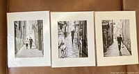 Three matted black-and-white photographic prints laid out side by side