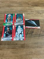 All five Topps Star Wars: The Last Jedi trading cards laid out on wooden surface