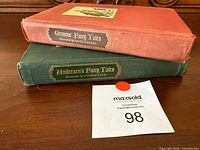 Two hardcover fairy-tale books stacked, showing spine titles and cloth colours