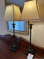 Both matching bronze table lamps with shades on dresser