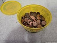 Yellow margarine container filled with pennies