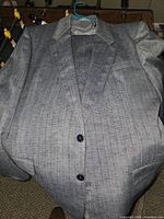 Front view of light grey pinstriped suit jacket on hanger