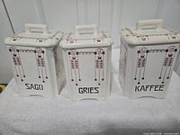 Front view of three large canisters showing pattern, lettering, lids