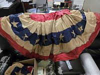 Pleated half-circle bunting flag showing red, tan and navy bands with embroidered stars