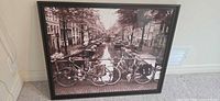 Overall view of framed sepia Amsterdam canal print leaning against wall