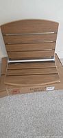 Teak slatted folding shower seat with stainless hardware on shipping box