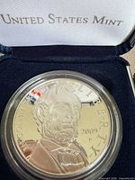 Obverse of coin in capsule inside presentation box