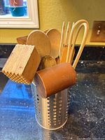 Utensil holder with mixed wooden utensils and silicone-tipped tongs, front view