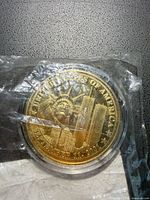 Obverse of gold-colored 9/11 commemorative round in plastic capsule