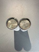 Two unopened white quarter rolls showing end coins, Washington obverse and Theodore Roosevelt NP reverse visible