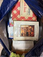 Bag containing multiple cookbooks including Fannie Farmer and red-check hardcover