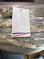 Four resealable bags filled with state quarters and handwritten state checklist card