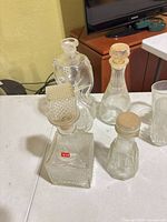 four clear glass decanters/bottles with stoppers visible