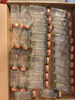 Box of multiple glass spice jars with lids