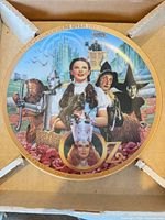 Front of commemorative plate showing full illustration and gold rim in original packaging