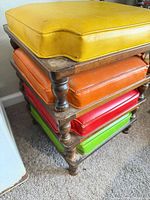 Full view of stacked ottoman showing four colored cushions and wooden frame