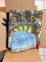Fabric items stacked in box: bandanas/flags visible