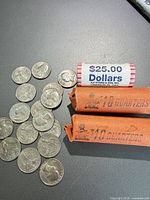 Loose quarters, two quarter rolls, one $25 dollar coin roll visible