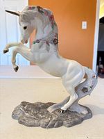 Side view of rearing porcelain unicorn with floral details and gold accents