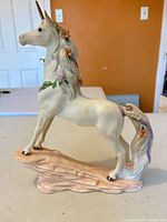 Left-front view of porcelain unicorn showing floral garlands and gold horn